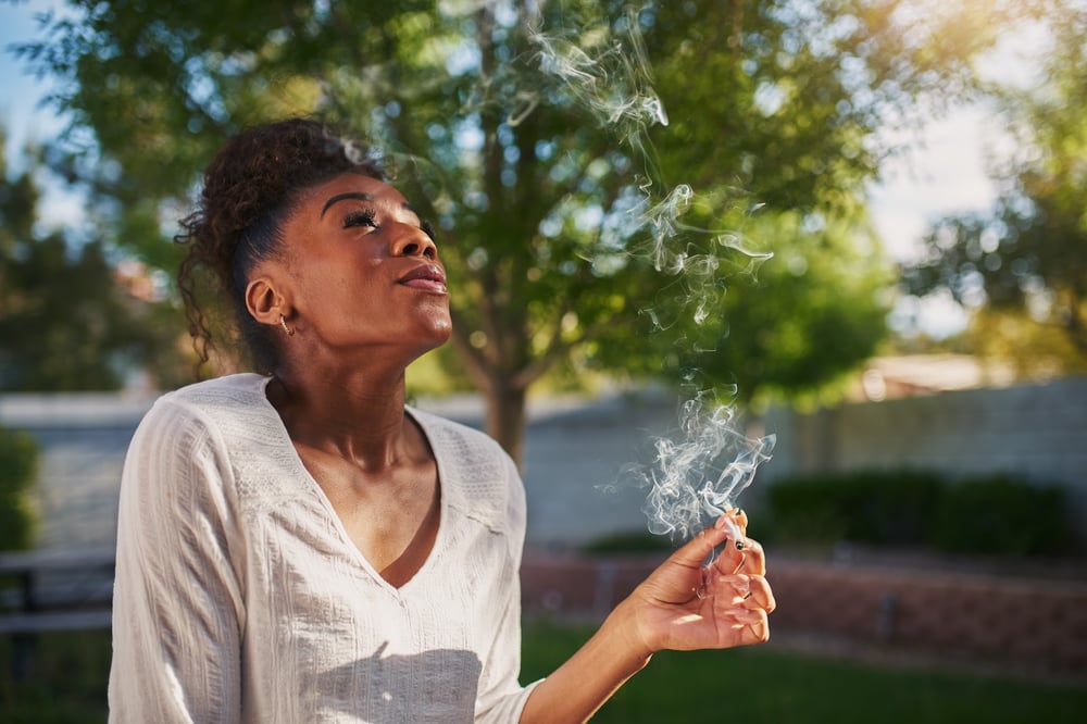 A young woman enjoying a joint outside on a nice day.